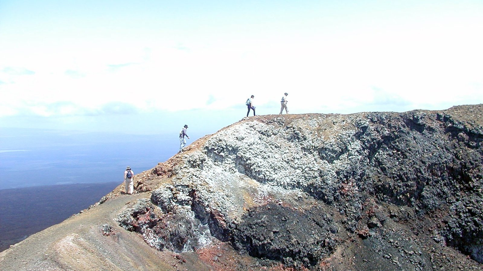 Group of travelers hiking along the rim of a volcanic crater in the Galápagos Islands, Ecuador.