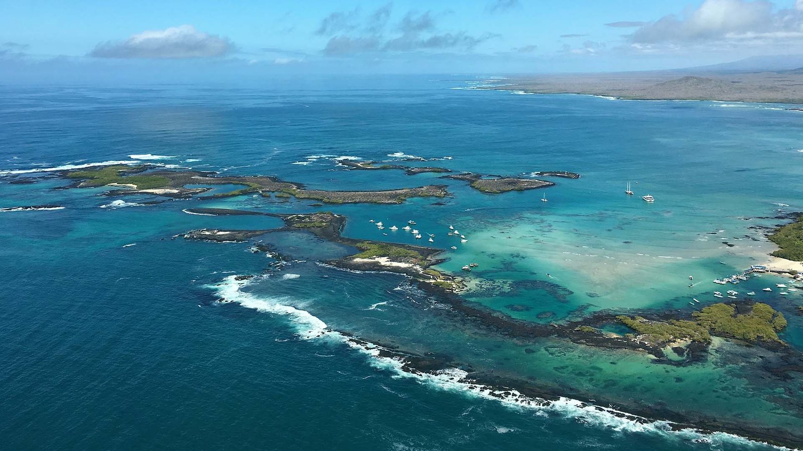 Aerial photo of turquoise waters, islets, and boats in the Galápagos Islands, Ecuador.